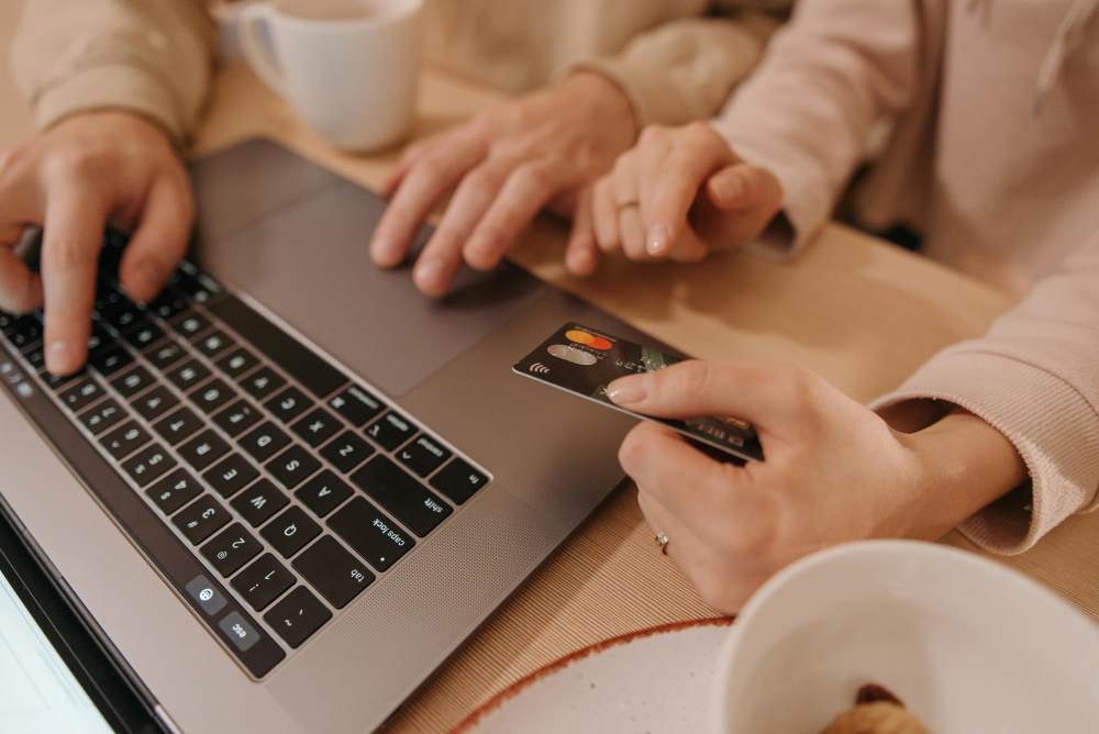 A person using a credit card with a laptop